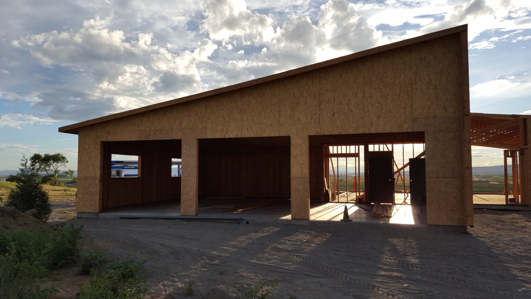 Front elevation of wood-framed building with open garage bays