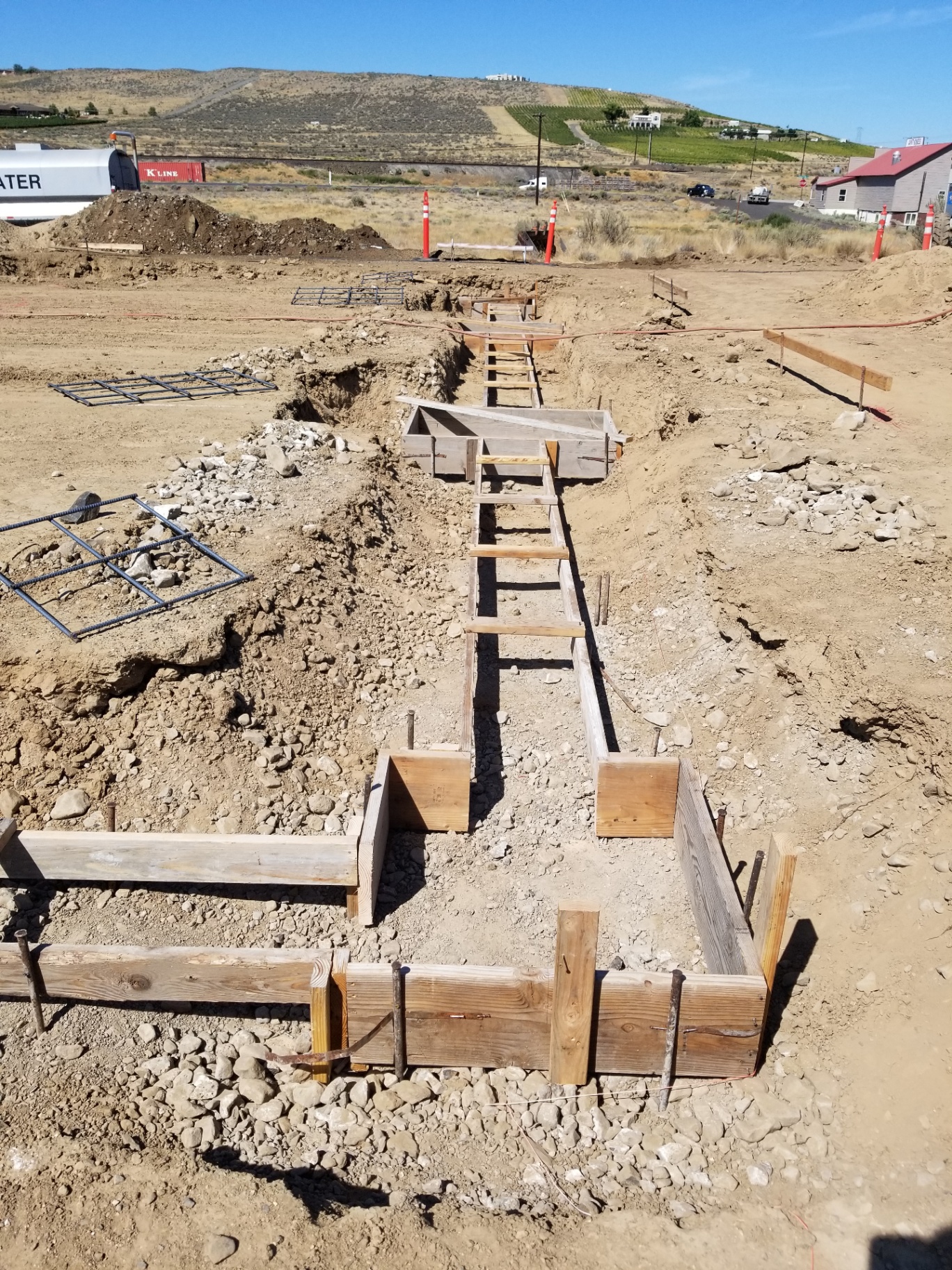 Long-run footing forms across a building pad