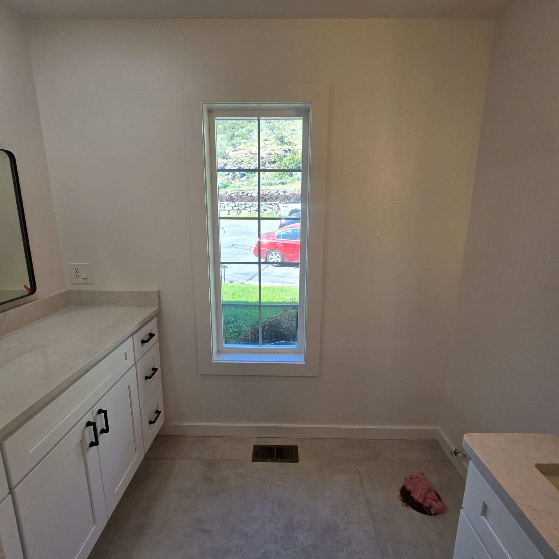 Bathroom remodel — dual vanities with quartz countertops flanking a tall picture window